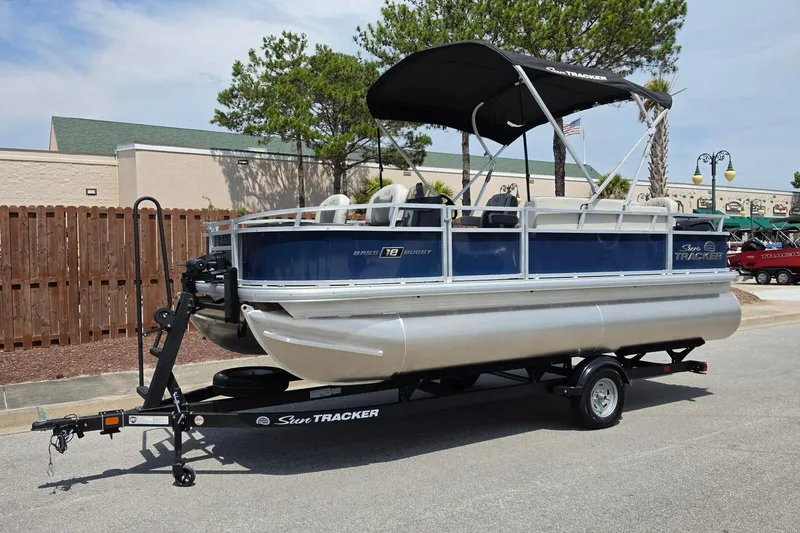 Slide: The Image of 2026 Sun Tracker Bass Buggy 18 DLX pontoon boat on trailer, parked outdoors. - 12
