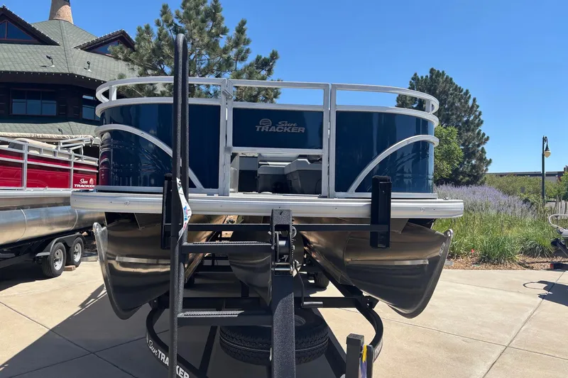 Slide: The Image of 2026 Sun Tracker Sportfish 24 XP3 pontoon boat on trailer, parked outdoors. - 2