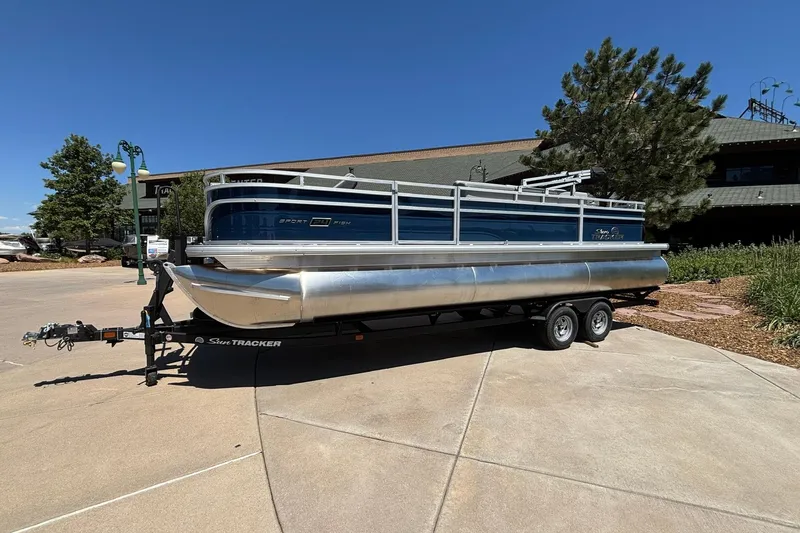 The Image of 2026 Sun Tracker Sportfish 24 XP3 pontoon boat on trailer, parked outdoors. - 0