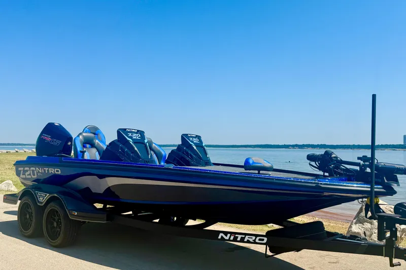 The Image of 2026 Nitro Z20 XL Pro boat on trailer by a serene lake under clear blue sky. - 0