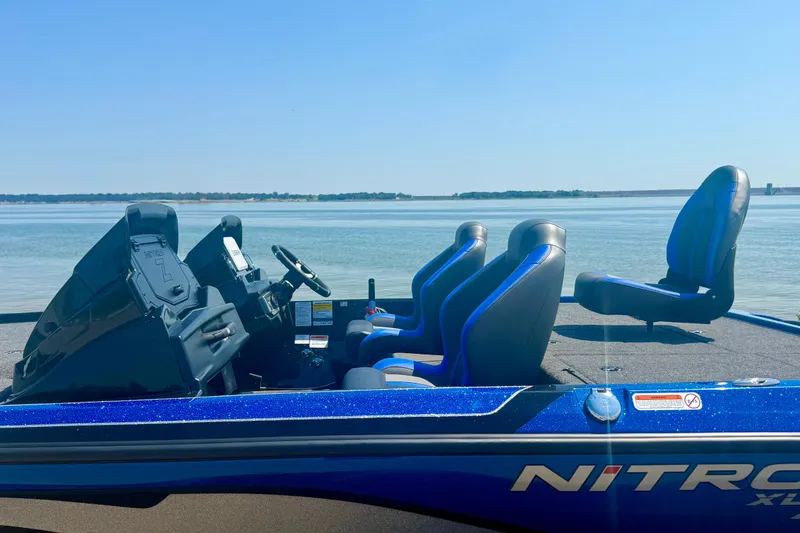 Slide: The Image of 2026 Nitro Z20 XL Pro boat with blue seats, docked by a serene lake. - 10