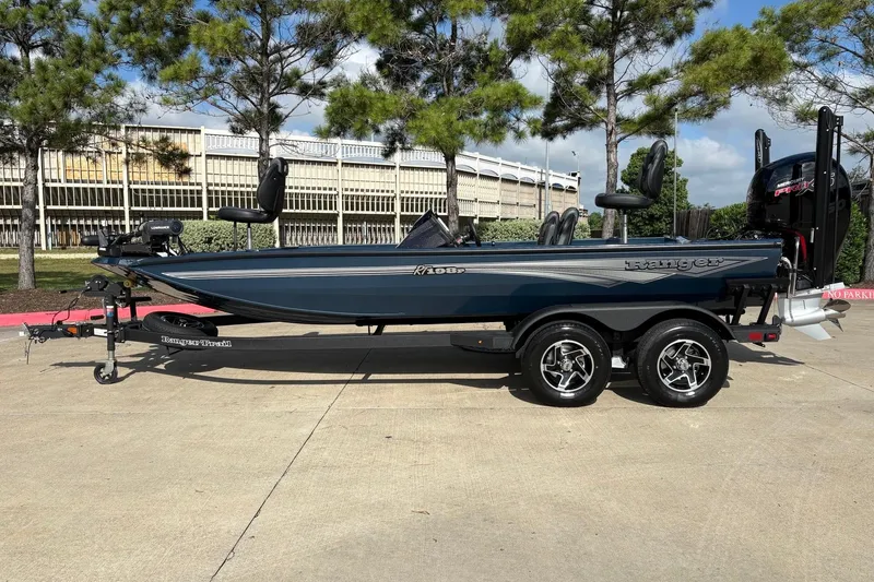 Slide: The Image of 2026 Ranger RT198P fishing boat on trailer, parked outdoors with trees in background. - 85