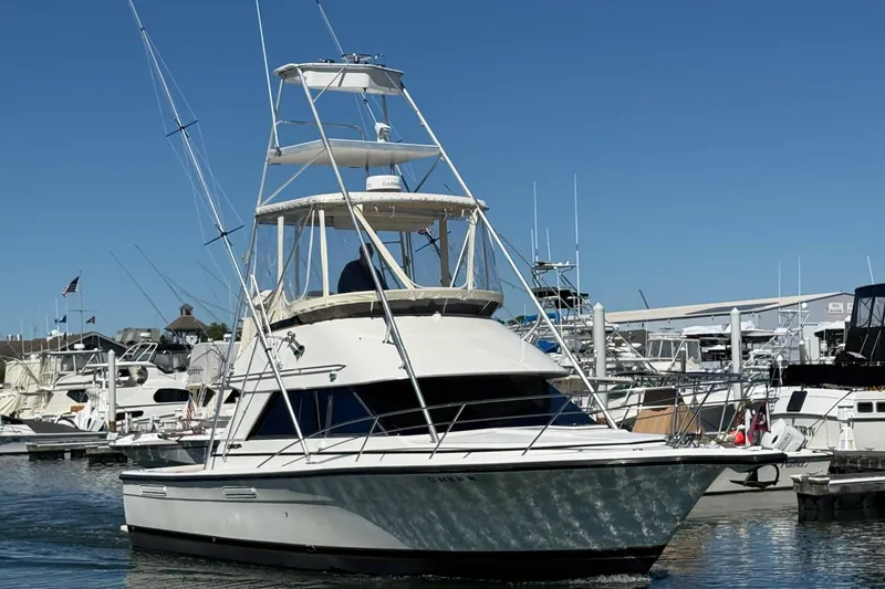 Slide: The Image of 1987 Phoenix 34 SFX Convertible yacht docked at marina under clear blue sky. - 3