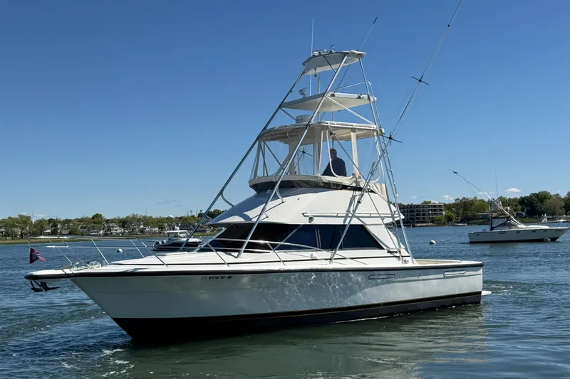 Slide: The Image of 1987 Phoenix 34 SFX Convertible boat on calm water under clear blue sky. - 4