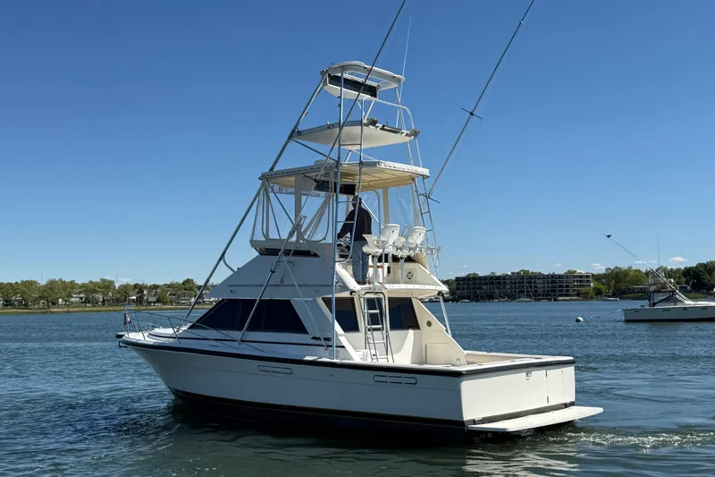 Slide: The Image of 1987 Phoenix 34 SFX Convertible boat on calm water under clear blue sky. - 9