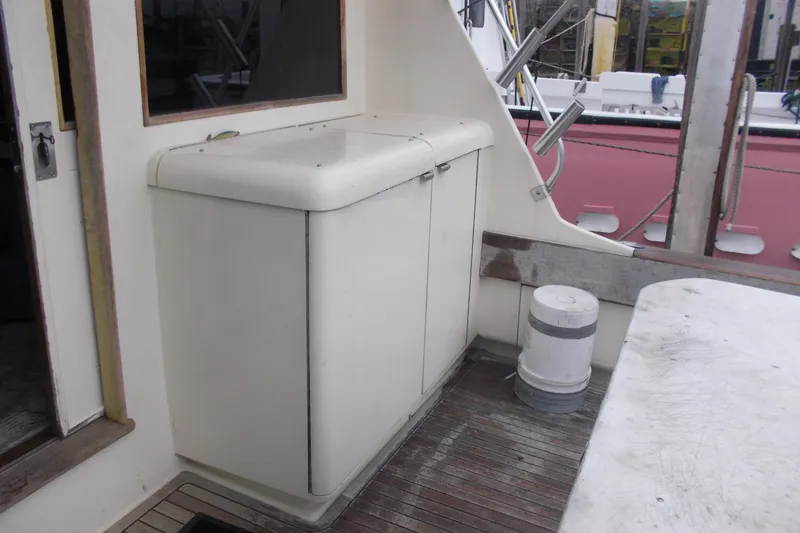 Slide: The Image of 1982 Hatteras 46 Convertible yacht deck with storage cabinet and wooden flooring. - 16