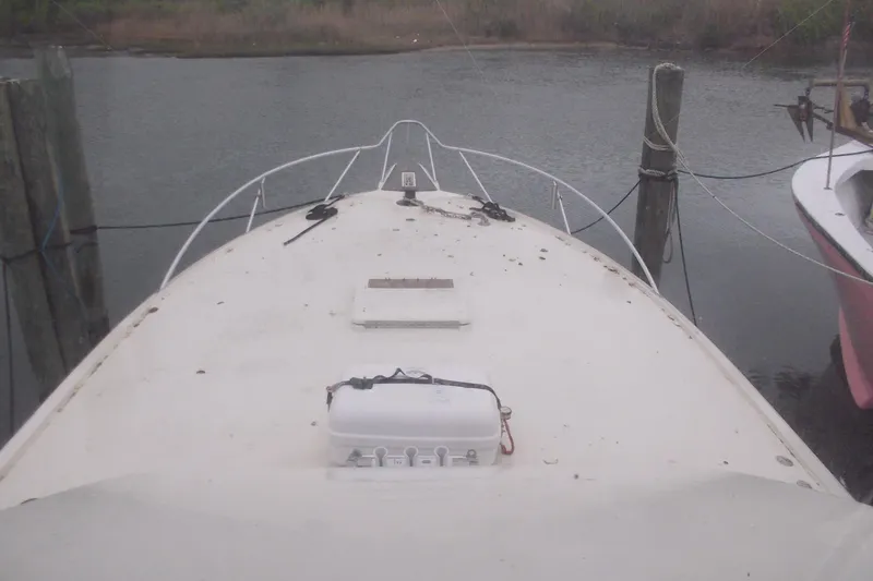 Slide: The Image of 1982 Hatteras 46 Convertible boat docked, view from bow, calm water background. - 18