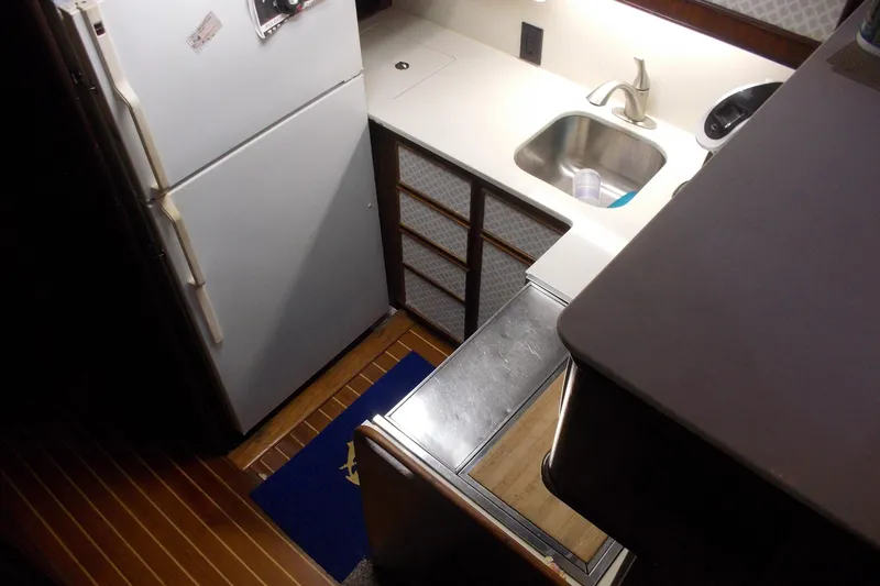 Slide: The Image of Compact kitchen area in a 1982 Hatteras 46 Convertible yacht, featuring a sink and refrigerator. - 5