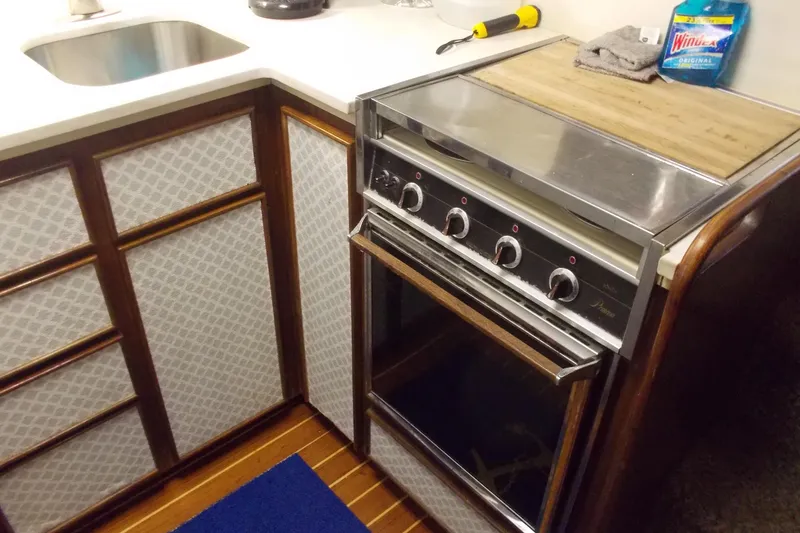 Slide: The Image of 1982 Hatteras 46 Convertible yacht kitchen with stove, sink, and wooden cabinetry. - 6