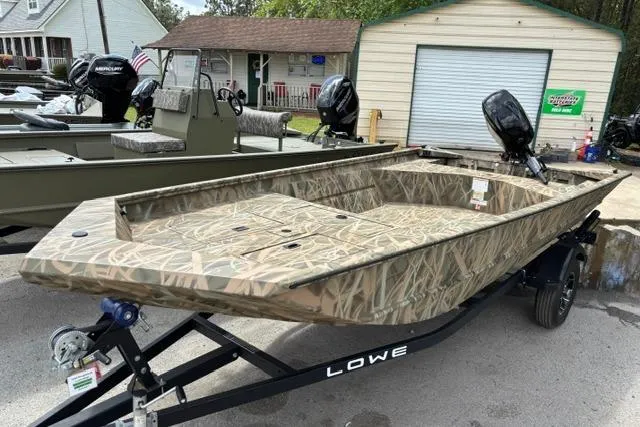Slide: The Image of 2026 Lowe Roughneck 1660 Deluxe Tiller boat with camouflage design on a trailer. - 2