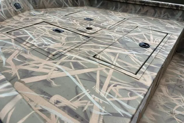 Slide: The Image of 2026 Lowe Roughneck 1660 Deluxe Tiller boat deck with camouflage pattern and storage compartments. - 3