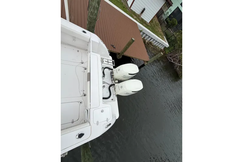 Slide: The Image of 2017 Pro-Line 29 Grand Sport boat with dual outboard motors docked by a wooden pier. - 14