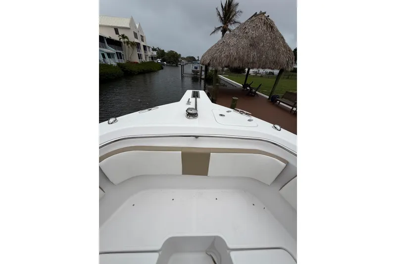Slide: The Image of 2017 Pro-Line 29 Grand Sport boat docked near waterfront homes and a thatched-roof hut. - 19