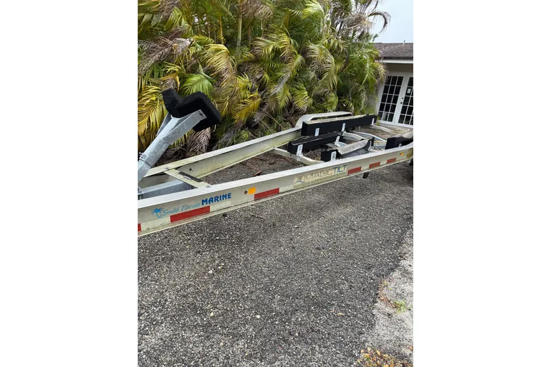 Slide: The Image of Boat trailer for 2017 Pro-Line 29 Grand Sport, parked near tropical foliage. - 27
