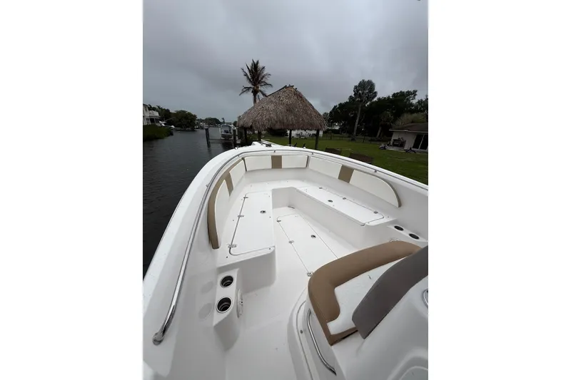 Slide: The Image of 2017 Pro-Line 29 Grand Sport boat with spacious seating, docked near a canal under cloudy skies. - 7