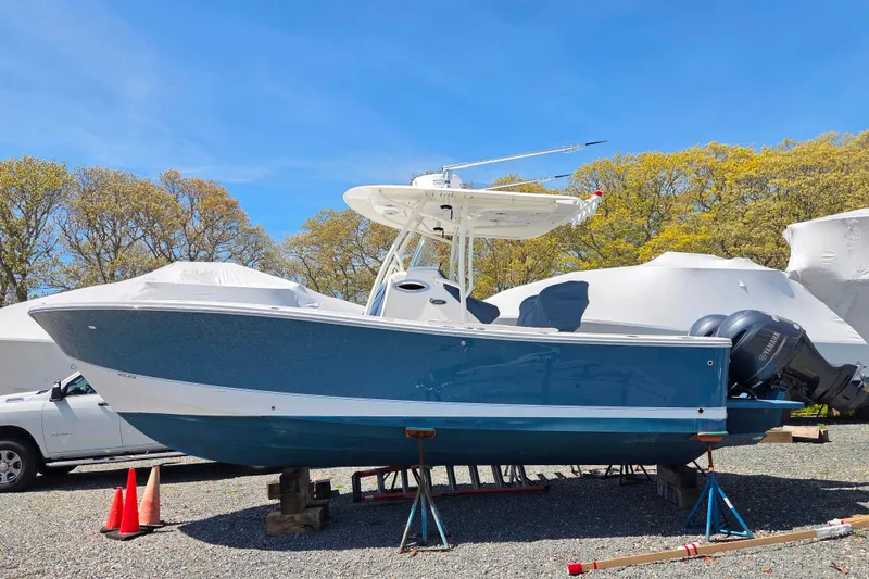 Slide: The Image of 2014 Regulator 25 boat on stands, blue hull, twin engines, outdoor storage. - 1