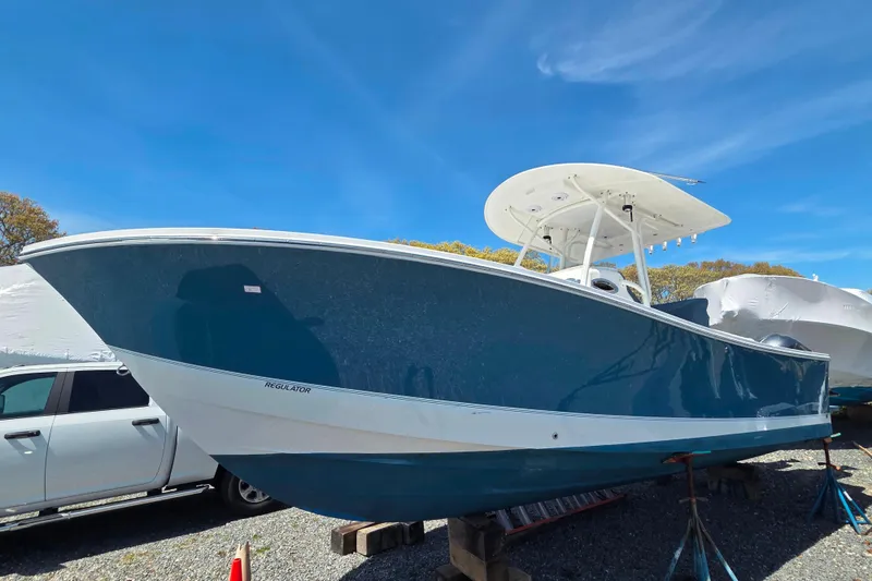 Slide: The Image of 2014 Regulator 25 boat on stands under clear blue sky. - 2