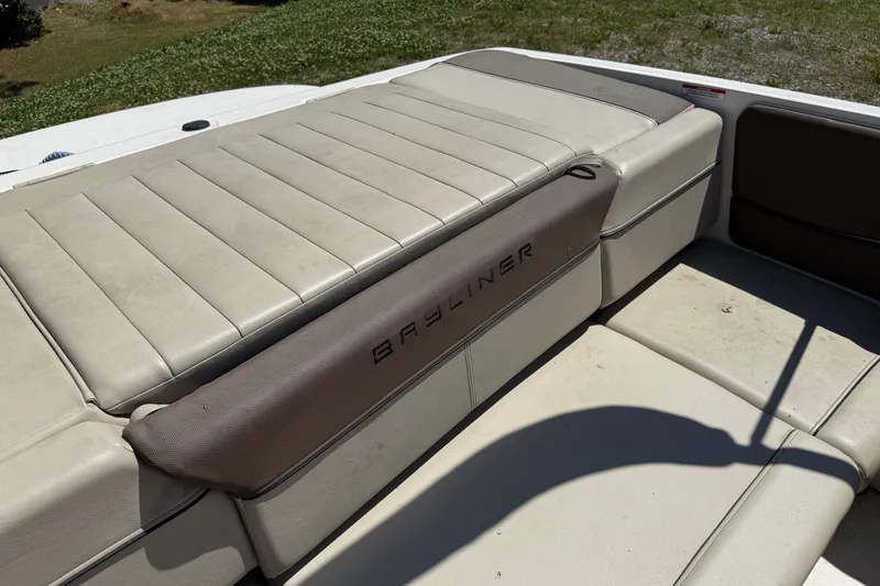 Slide: The Image of 2015 Bayliner 185 Bowrider boat interior with beige seating and Bayliner logo. - 9