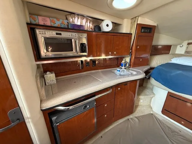Slide: The Image of 2007 Sea Ray 320 Sundancer interior with kitchenette and bed, featuring wood cabinetry and modern amenities. - 16