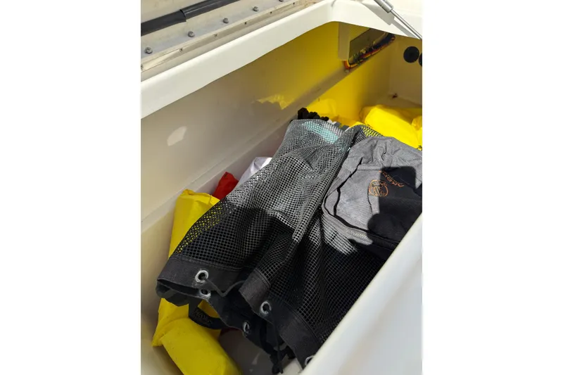 Slide: The Image of Storage compartment in a 2023 World Cat 255 DC boat with gear and clothing. - 17