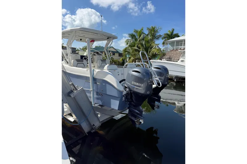 Slide: The Image of 2023 World Cat 255 DC boat with twin Yamaha engines docked by palm trees. - 4