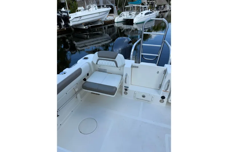 Slide: The Image of 2023 World Cat 255 DC boat interior with seating and ladder, docked near other boats. - 6
