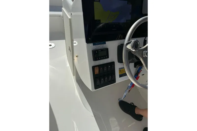 Slide: The Image of 2023 World Cat 255 DC boat dashboard with steering wheel and control panel. - 9