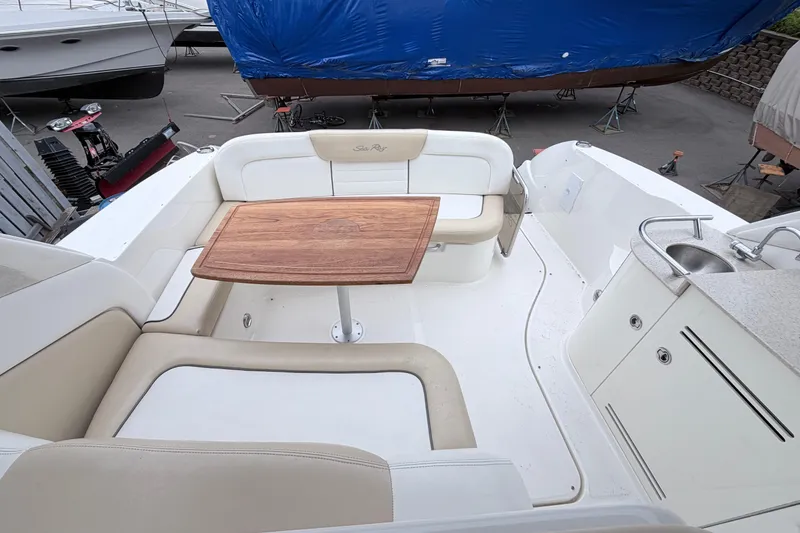 Slide: The Image of 2008 Sea Ray Sundancer 330 cockpit with seating, wooden table, and sink area. - 5