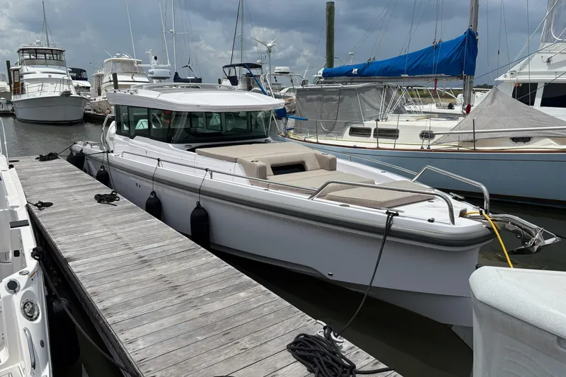 Slide: The Image of 2024 Axopar 37 XC Cross Cabin docked at a marina under cloudy skies. - 2