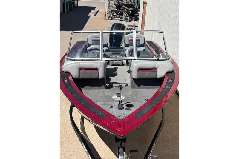 Slide: The Image of 2016 Bass Tracker Tournament V-18 boat with red and gray interior, docked outdoors. - 2