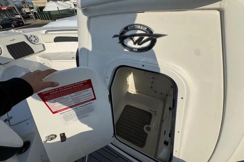 Slide: The Image of 2026 Tidewater 232 SS boat storage compartment with open hatch and warning label. - 23