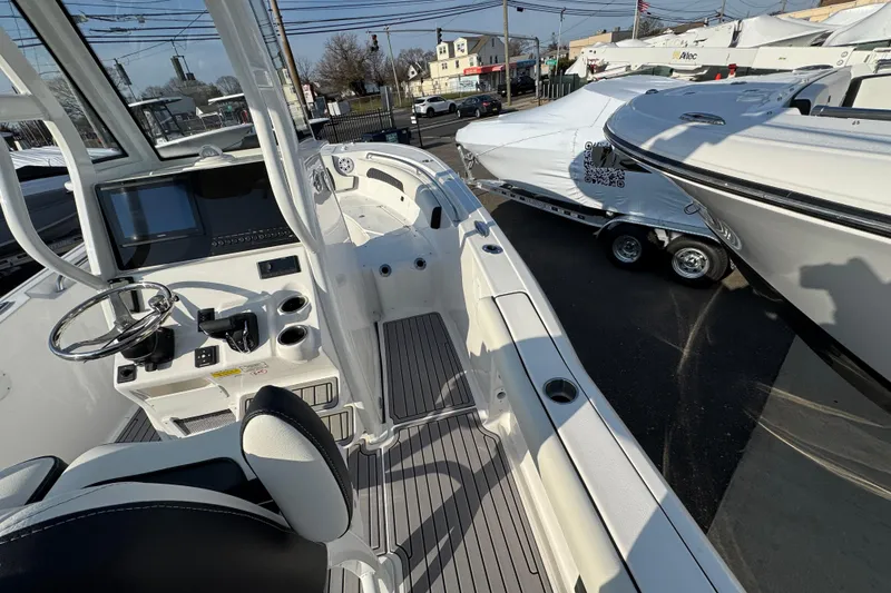 Slide: The Image of 2026 Tidewater 232 SS boat interior with steering wheel and control panel, docked outdoors. - 24