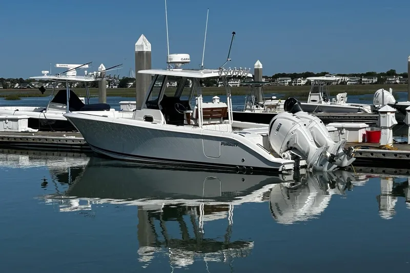 Slide: The Image of 2024 Pursuit S 288 Sport boat docked in a marina, reflecting on calm water. - 12