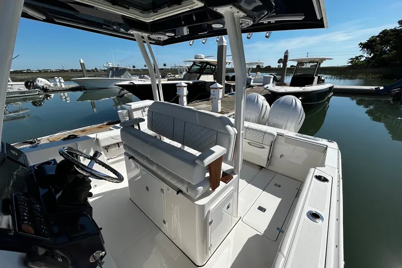 Slide: The Image of 2024 Pursuit S 288 Sport boat docked at marina, showcasing sleek interior and helm. - 8