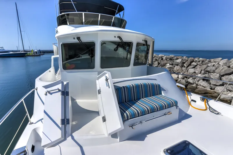 Slide: The Image of 2003 Jefferson Pilothouse 57 yacht with striped seating, docked by rocky shoreline. - 9