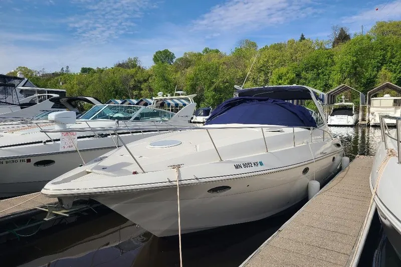 The Image of 2006 Cruisers Yachts 3470 Express docked at marina, surrounded by lush greenery. - 0