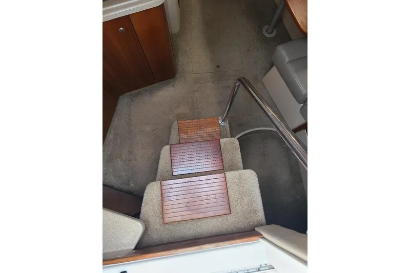 Slide: The Image of Interior stairs of 2006 Cruisers Yachts 3470 Express with wooden steps and carpeted flooring. - 12