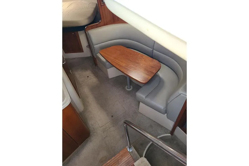 Slide: The Image of 2006 Cruisers Yachts 3470 Express interior with curved seating and wooden table. - 13
