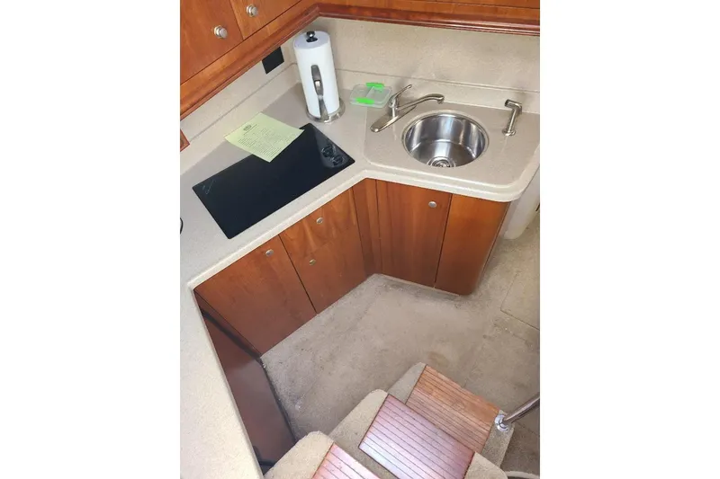 Slide: The Image of 2006 Cruisers Yachts 3470 Express kitchen with sink, stovetop, and wooden cabinetry. - 15