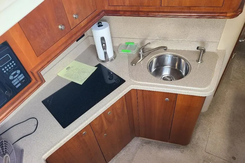 Slide: The Image of 2006 Cruisers Yachts 3470 Express kitchen with sink, stove, and wooden cabinetry. - 19