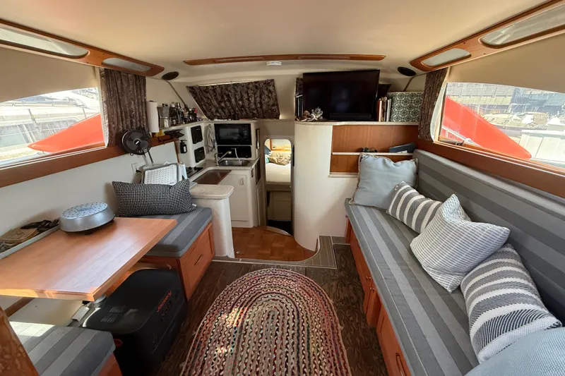 Slide: The Image of Interior of 1998 Luhrs Tournament 320 Convertible boat, featuring cozy seating and a compact kitchen. - 15