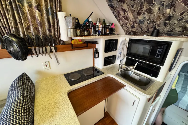 Slide: The Image of Compact kitchen in a 1998 Luhrs Tournament 320 Convertible boat, featuring stove, sink, and microwave. - 19
