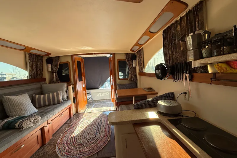 Slide: The Image of Interior of 1998 Luhrs Tournament 320 Convertible boat, featuring cozy seating and kitchenette. - 20