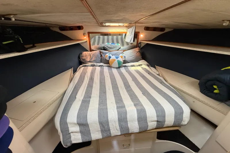 Slide: The Image of 1998 Luhrs Tournament 320 Convertible cabin with striped bedding and cozy interior. - 23