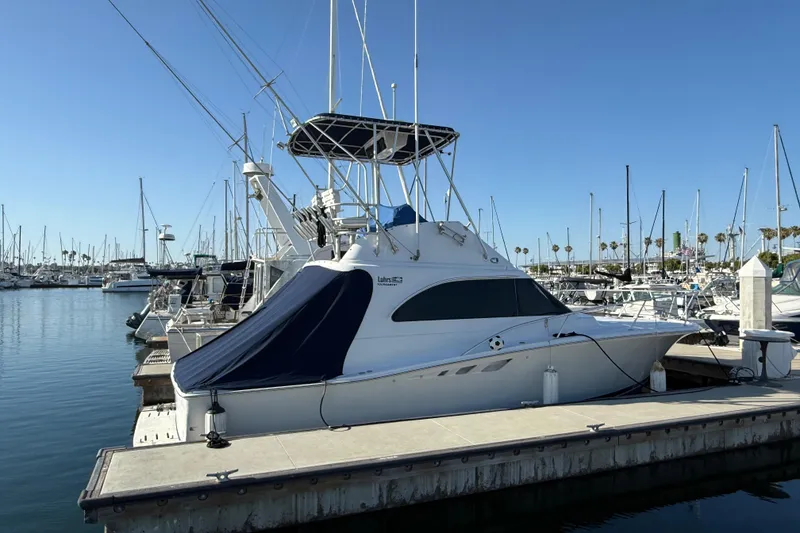 Slide: The Image of 1998 Luhrs Tournament 320 Convertible yacht docked at a marina under clear blue skies. - 3