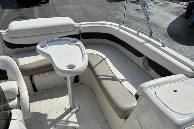 Slide: The Image of 2006 Tahoe 195 I/O boat interior with seating and table, featuring white and beige upholstery. - 2