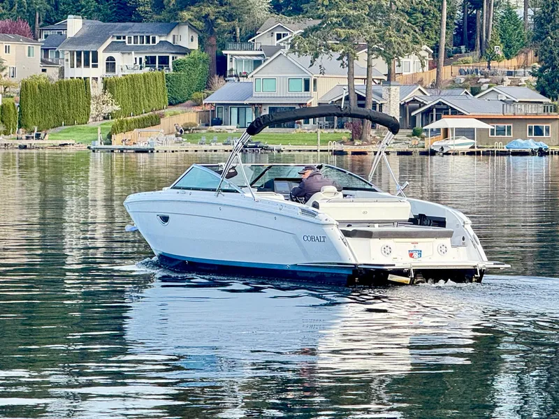 Slide: The Image of 2023 Cobalt R8 boat cruising on a serene lake near waterfront homes. - 11