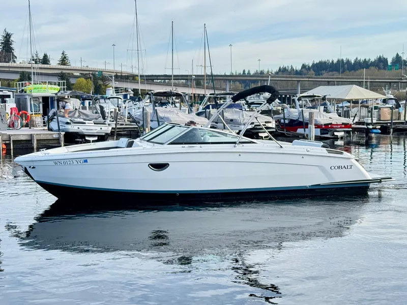 Slide: The Image of 2023 Cobalt R8 boat docked in a marina, surrounded by other vessels. - 13