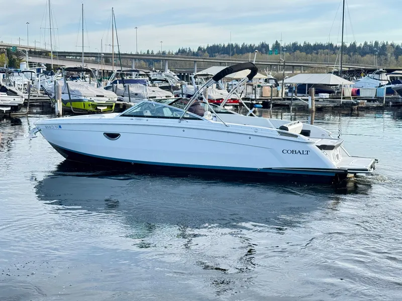 Slide: The Image of 2023 Cobalt R8 boat docked in a marina, surrounded by other vessels. - 14