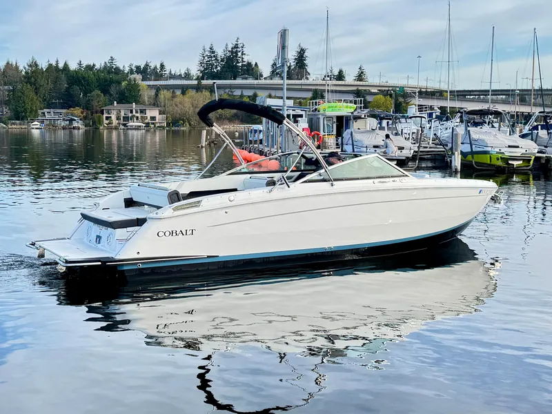 Slide: The Image of 2023 Cobalt R8 boat docked in a marina, surrounded by calm water and other vessels. - 21